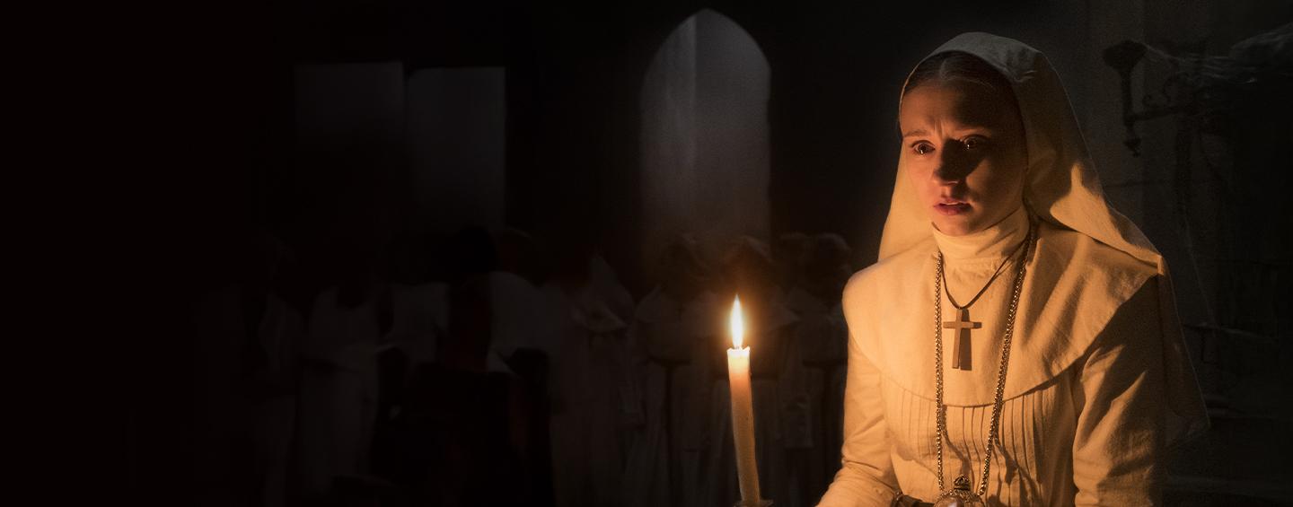 A nun holding a candle in a creepy room Desktop