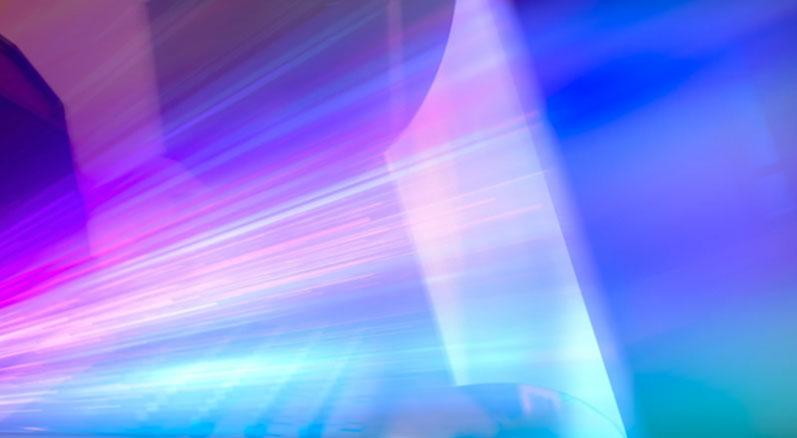 rays of purple and pink light illuminating a screen in an IMAX movie theatre